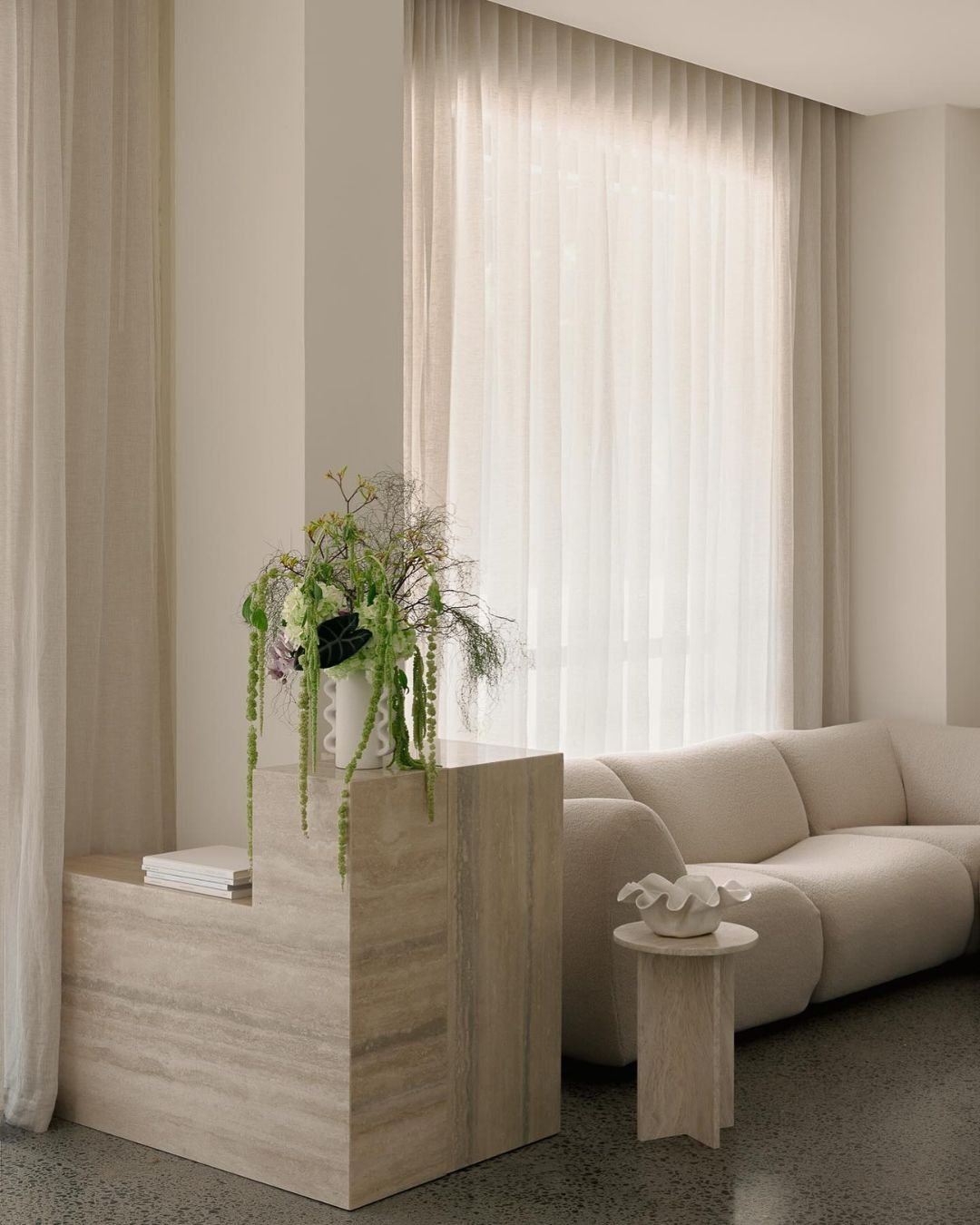 Small travertine side table styled in a living room.