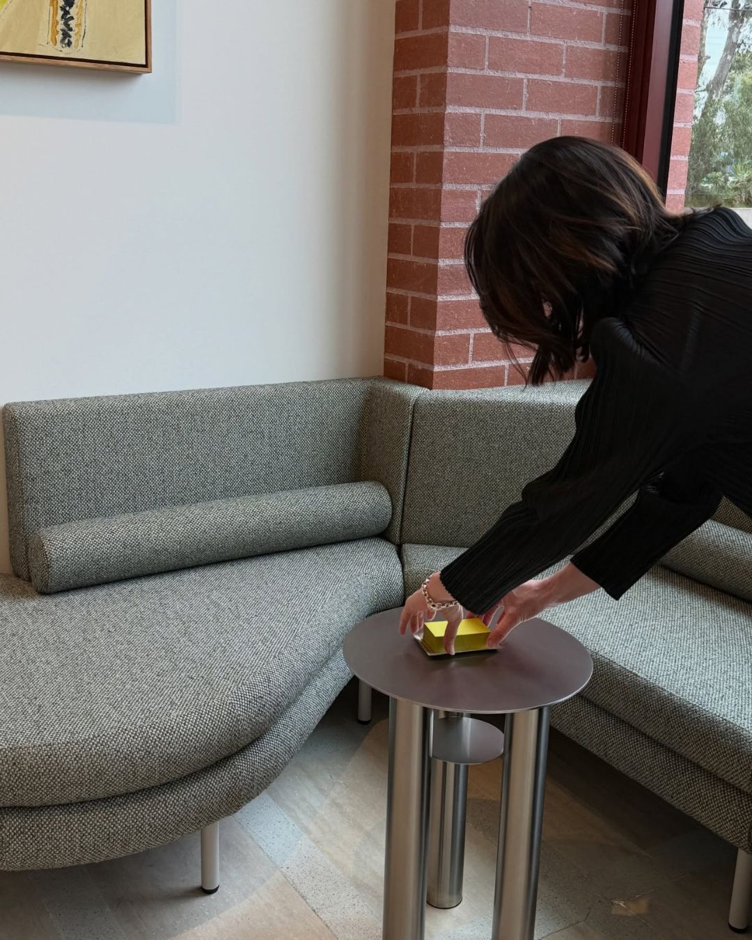Stainless steel side table being styling next to a green sofa.