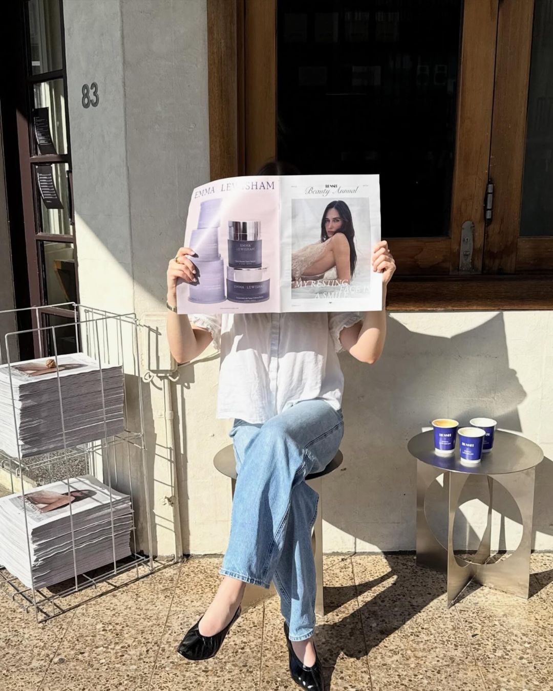 Person holding a newspaper sitting on a stainless steel stool