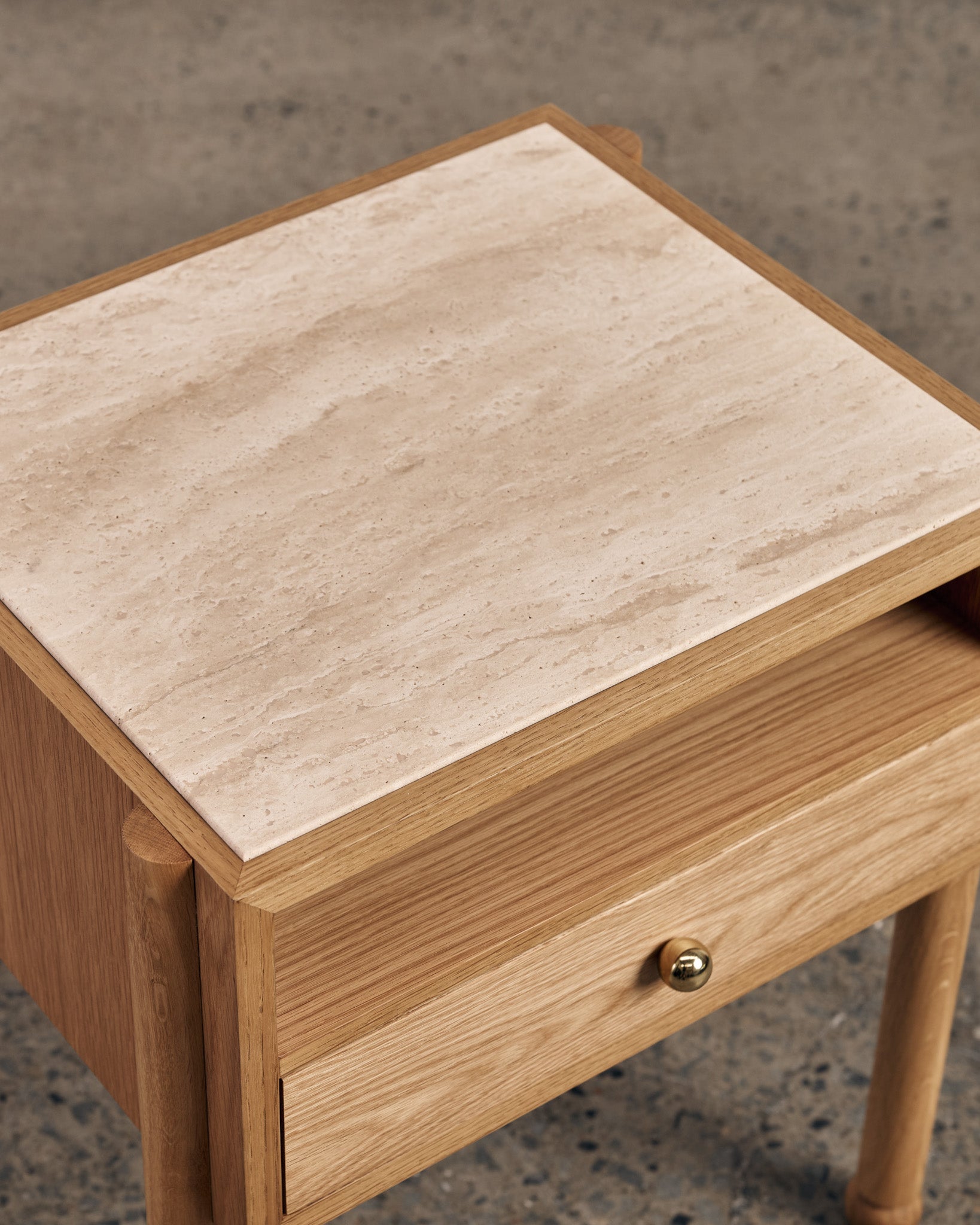 Close up detailing of an oak bedside table with a travertine top
