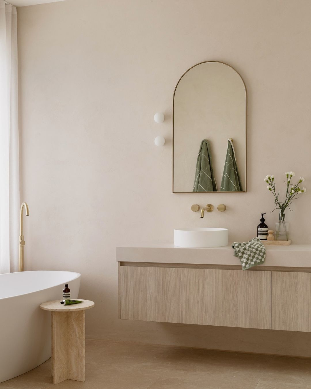 Small travertine side table styled in a bathroom