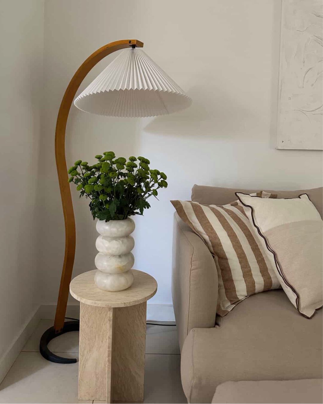 Small travertine side table styled in a living room.