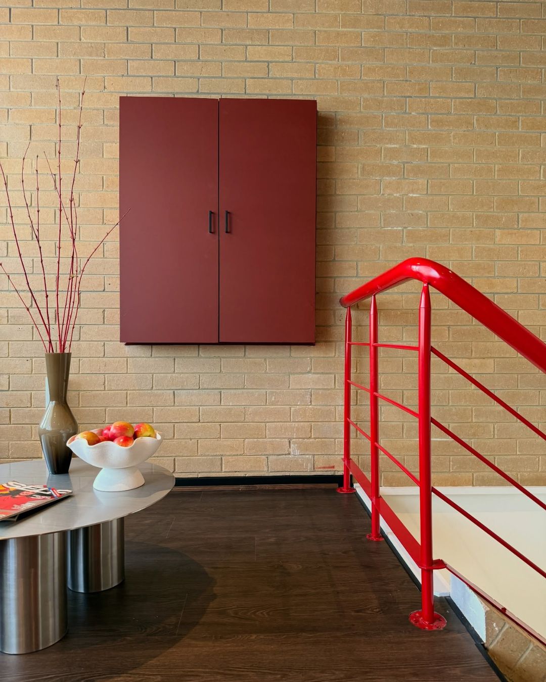 Modern interior with a red cabinet, red railing, and a table.